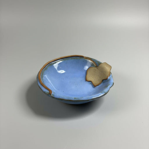 Small blue ceramic dish with a rustic leaf trim on a gray background