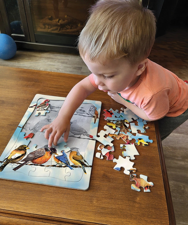 little kid putting together the Blue Sky Birds Tray Puzzle