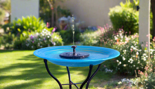 Blue bird bath with a solar fountain in a garden setting