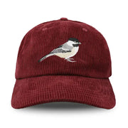 burgundy red corduroy cap with a bird embroidered on a white background