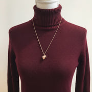 Necklace with an acorn pendant on a mannequin bust against a plain background
