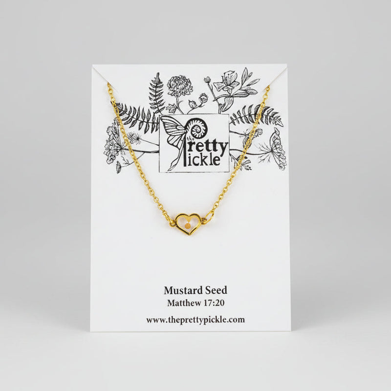 Gold necklace with heart pendant enclosing a mustard seed