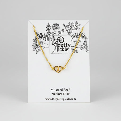 Gold necklace with heart pendant enclosing a mustard seed