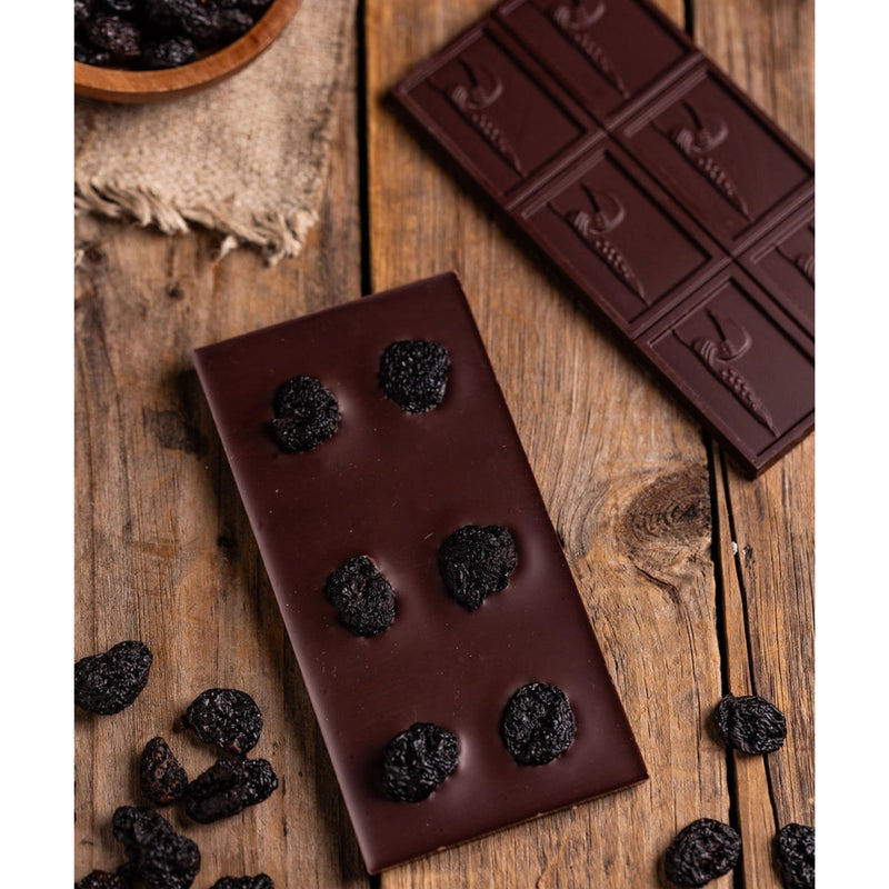 Chocolate Bar - Dark Chocolate with Dried Cherries on a rustic table with scattered dry cherries
