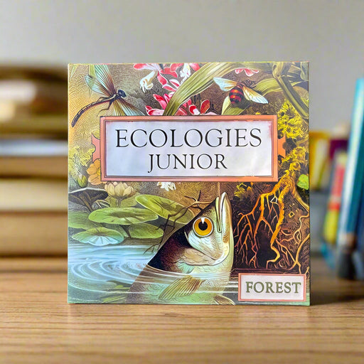 Board game box titled 'Ecologies Junior Forest' with nature-themed illustrations on a wooden surface.