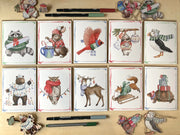 Set of greeting cards with animal illustrations wearing winter clothing on a wooden surface.