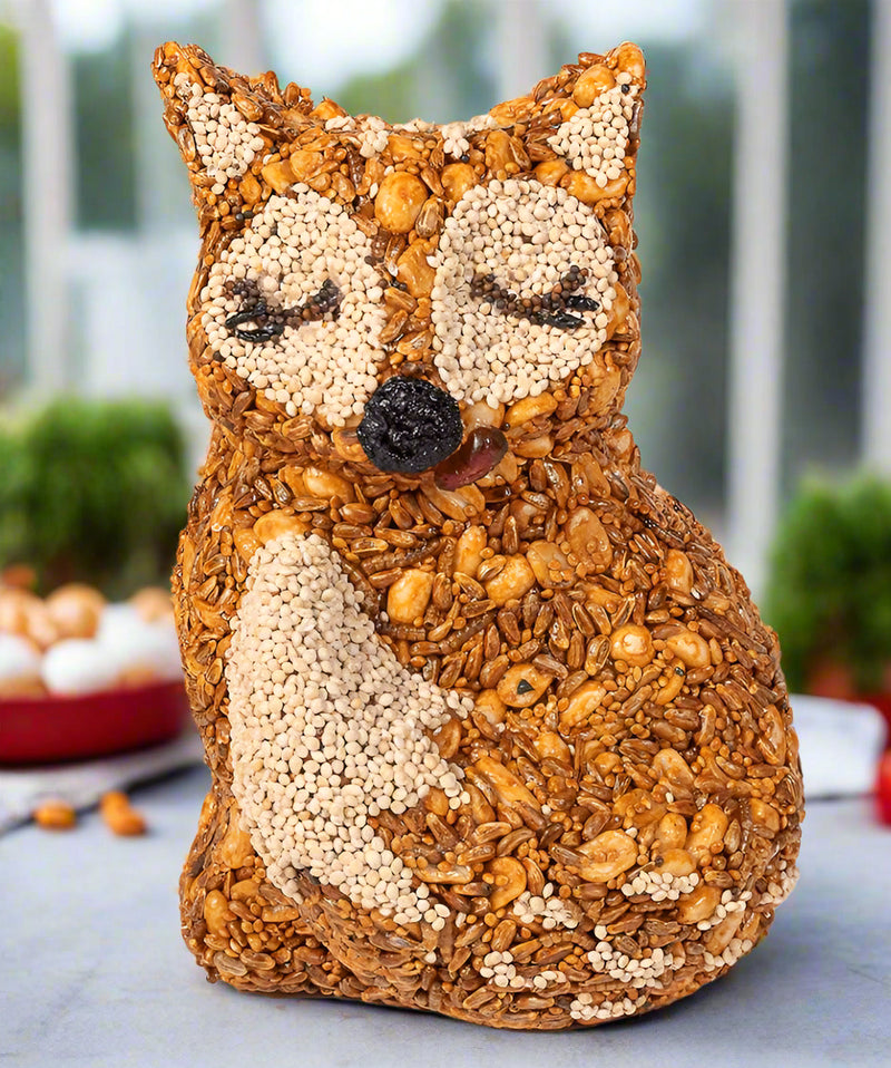 Fox-shaped bird ornament made of seeds, peanuts and mealworms on a blurred background