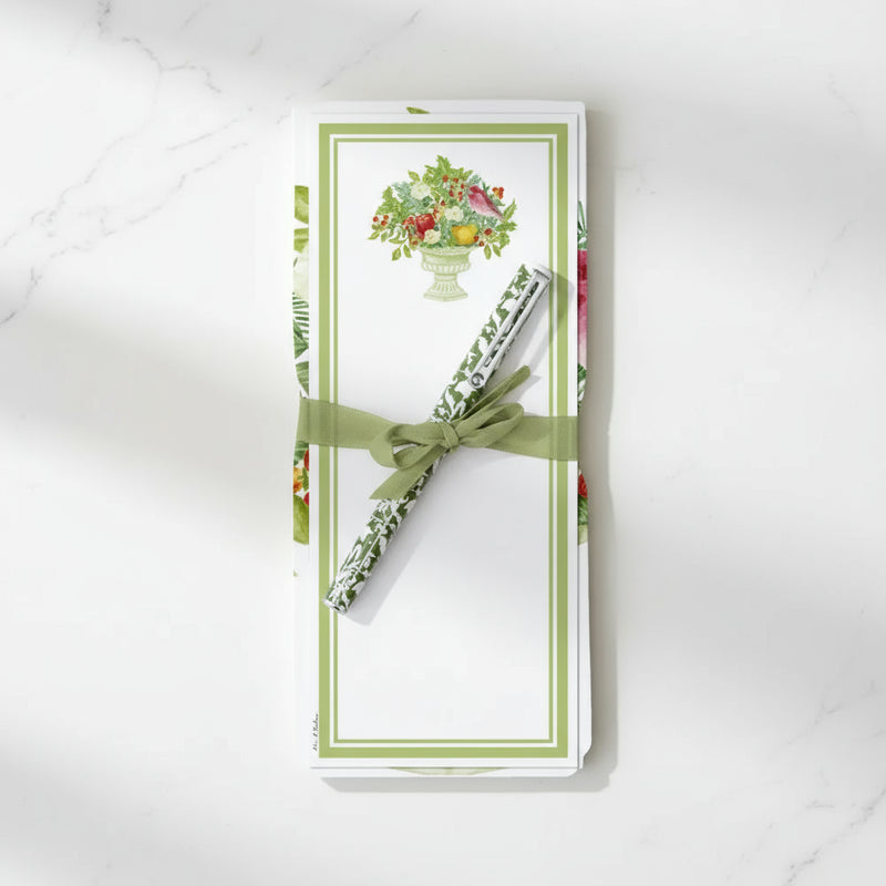 pen with a green bow on a decorative note pad with floral design