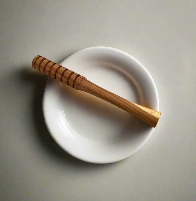 Wooden honey dipper on a white plate against a gray background