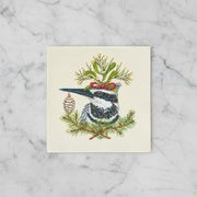 Paper napkin featuring a kingfisher bird, festive greens on a off-white background on a marble countertop
