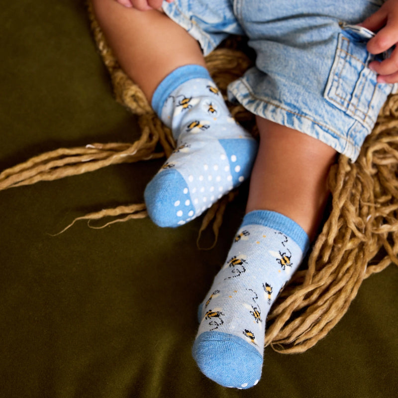 infant wearing light blue socks with bee pattern