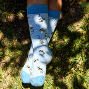Light blue socks with bee pattern being worn on child on the grass