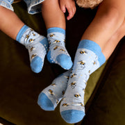 Two different size pairs of socks with bee patterns being worn by two children