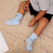 Child wearing light blue socks with bird patterns on a beige carpet