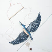Decorative kingfisher mobile with outstretched wings on a white surface with a ruler for scale.
