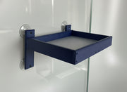 Blue wall-mounted tray on a piece of glass against a white wall 