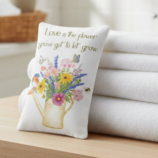 Watering Can Bluebird Bouquet Single Lavender Sachet propped against a stack of towels