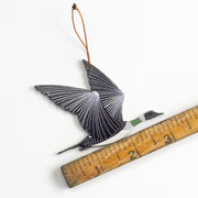 Decorative bird ornament with a ruler for scale on a white background