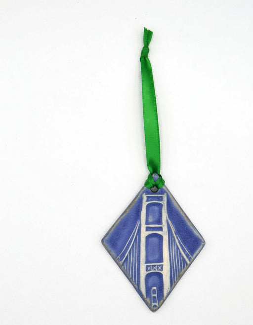 Two diamond-shaped ceramic ornaments with green ribbons on a white background