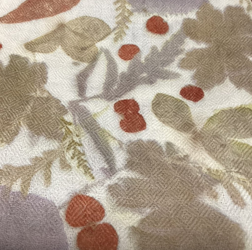 Close-up of a fabric with autumnal leaf pattern in brown, red, and beige on a white background.