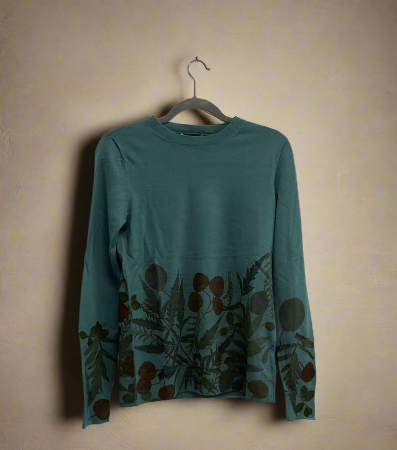 Teal long-sleeve sweater with floral pattern on a hanger against an off-white background - front view