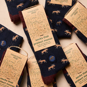 Navy socks with moose pattern and 'conscious step' packaging on a beige background