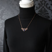 Necklace with a witch moth pendant on a mannequin bust against a dark background