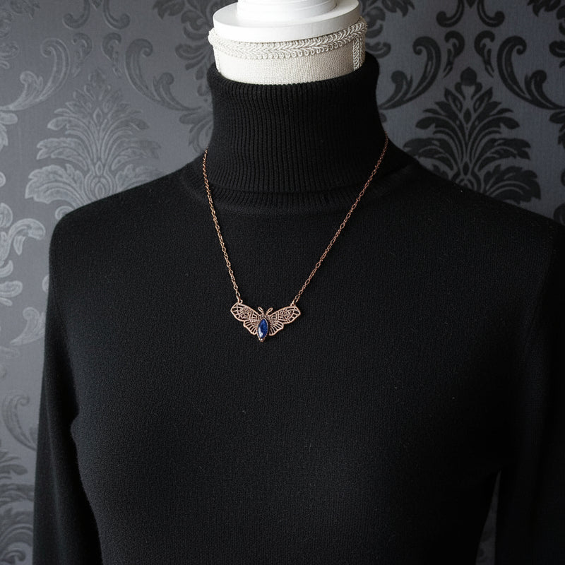 Necklace with a witch moth pendant on a mannequin bust against a dark background