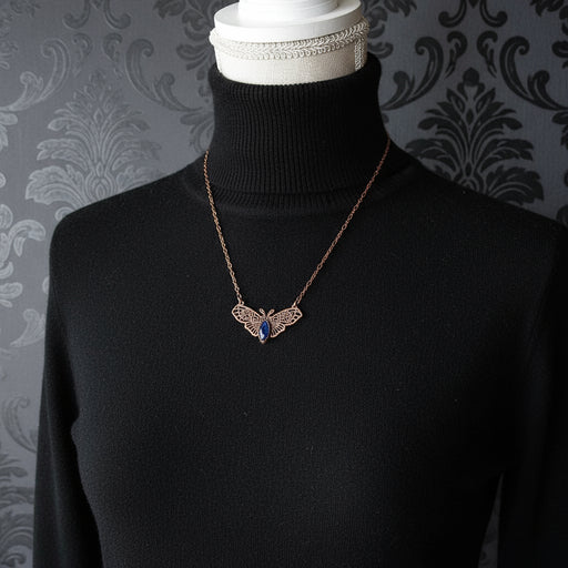 Necklace with a witch moth pendant on a mannequin bust against a dark background