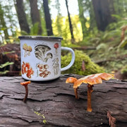 Mug with mushroom illustrations on a log in a forest setting