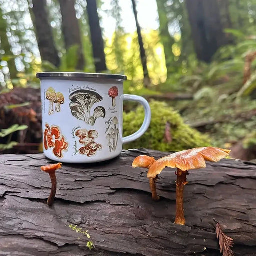 Mug with mushroom illustrations on a log in a forest setting