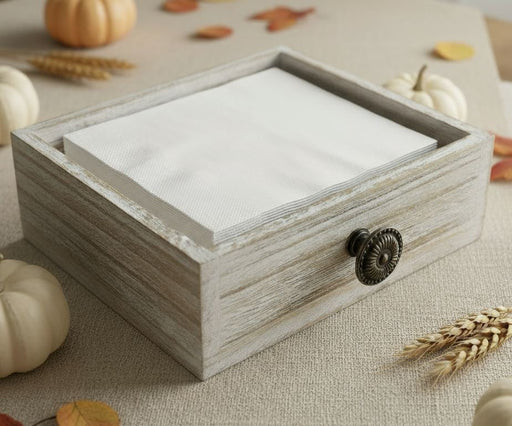Wooden napkin caddy holding white beverage napkins on a beige surface with autumn decorations.