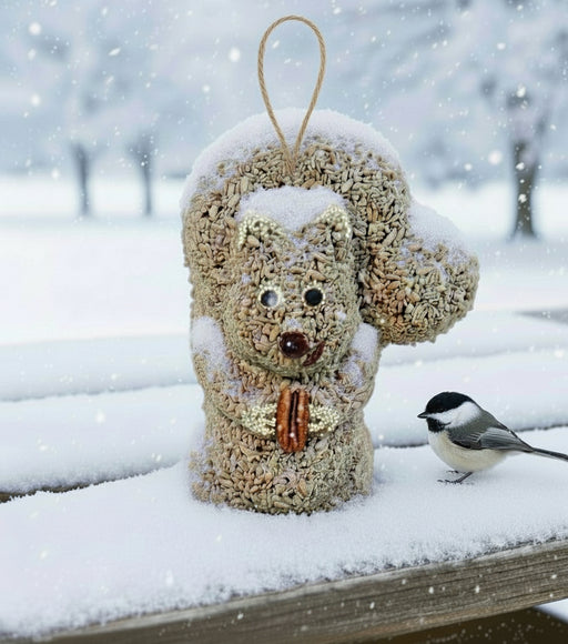 Bird feeder shaped like a squirrel with a chickadee perched on a snowy surface