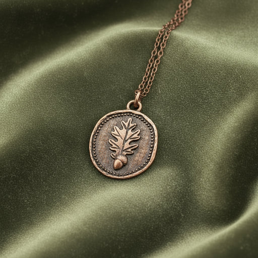 Copper necklace with an oak leaf and acorn pendant on a green background