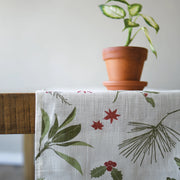 Table with a floral-patterned tablecloth and a potted plant on a neutral background