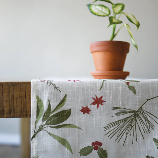 Table with a floral-patterned tablecloth and a potted plant on a neutral background