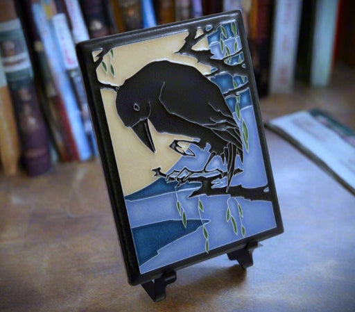 Decorative plaque with a raven design on a easel, set against a bookshelf background. (easel not included)