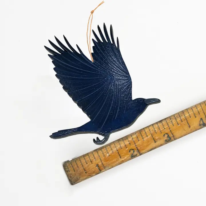 raven ornament on a wooden ruler against a white background