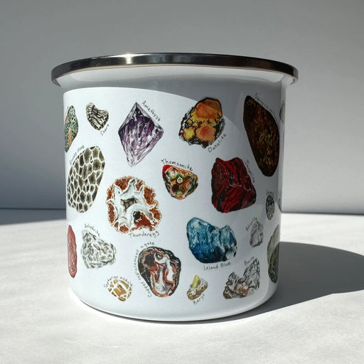 Enamel mug with illustrations of various gemstones on a white background