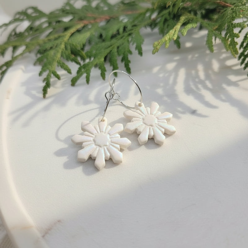 snowflake hoop earrings on a marble surface