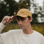 Sparrow Hat - Person wearing a mustard yellow cap with a blurred natural background