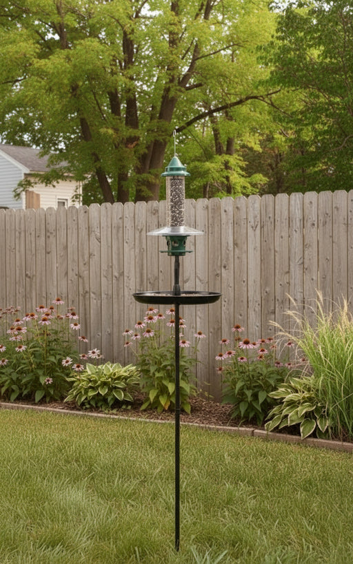 Bird feeder on a stand in a garden with autumn trees and flowers.