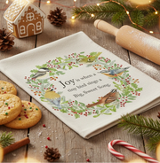 Towel with decorative wreath with birds and holly leaves, featuring a Christmas message.