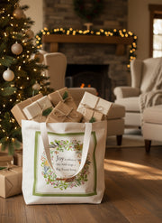Tote bag with bird design and text on a white background holding holiday presents by a Christmas tree