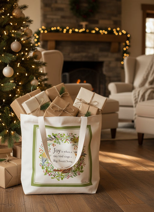 Tote bag with bird design and text on a white background holding holiday presents by a Christmas tree