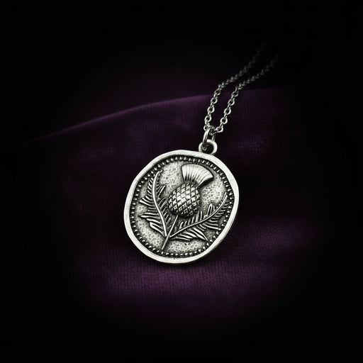 Silver necklace with a thistle pendant on a dark purple background