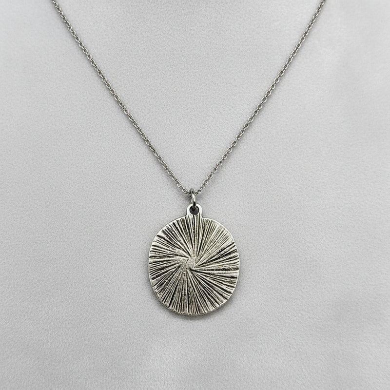Silver necklace with a textured circular pendant on a white background