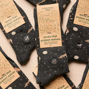 Dark gray folded socks with brown wolf and full moon patterns and 'conscious step' labels on socks