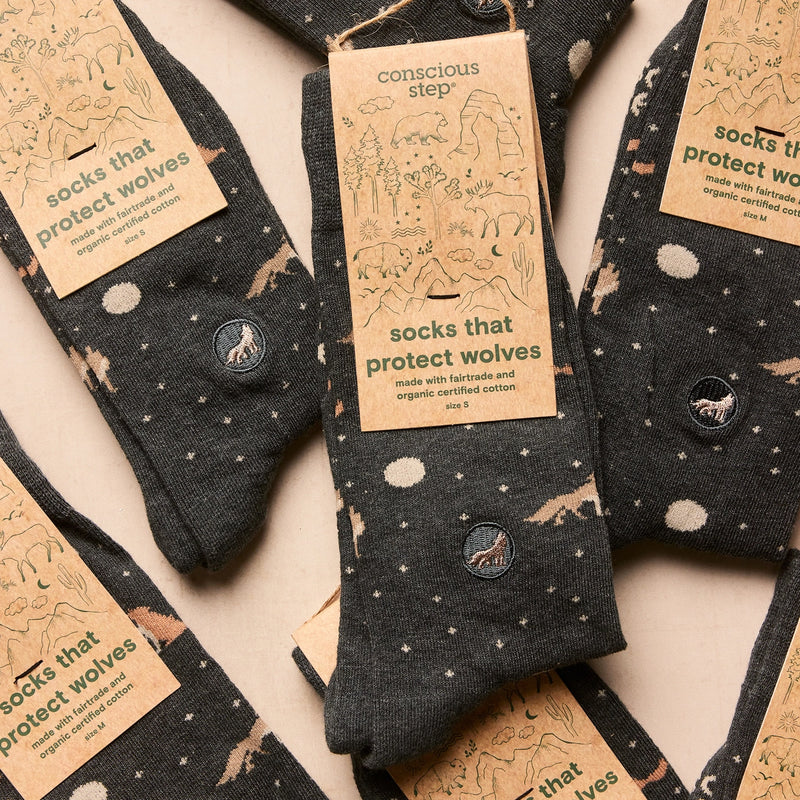 Dark gray folded socks with brown wolf and full moon patterns and 'conscious step' labels on socks