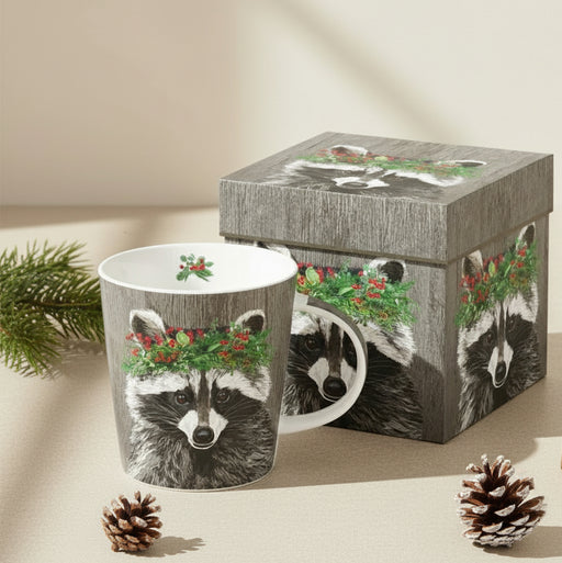 mug featuring a racoon wearing a festive evergreen crown on a grey wood background. comes inside a matching box 